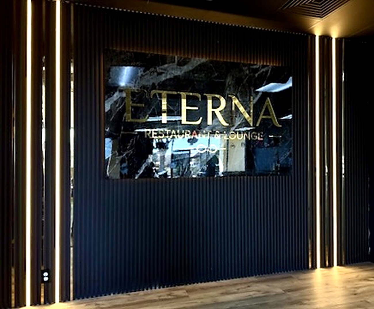 Gold Eterna Restaurant & Lounge sign on the black slat wall