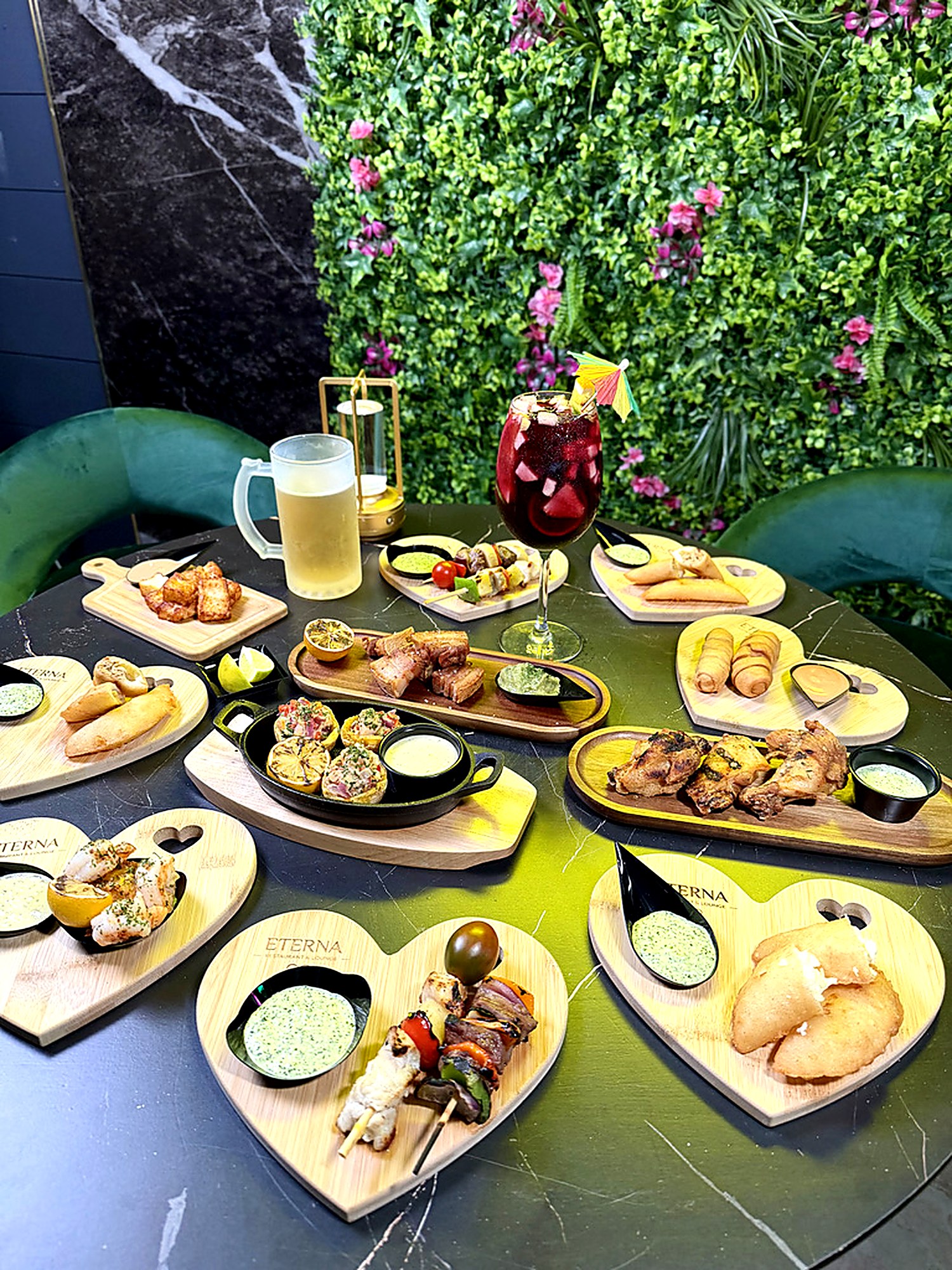 Tapas spread on heart-shaped Eterna boards with sangria and draft beer against the flower wall